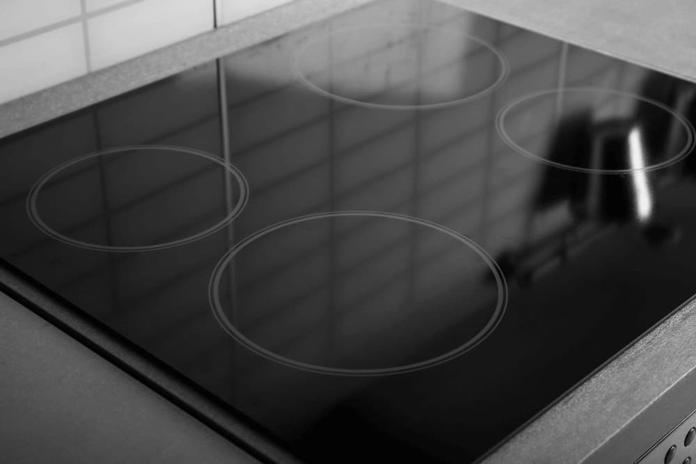 Close-up of a black induction hob's glass cooking surface showing the ring markings for each cooking zone