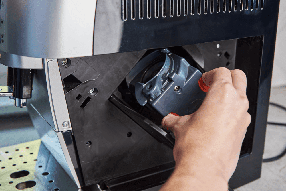 Hand removing the brew unit from a bean-to-cup coffee machine