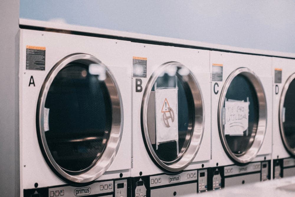 Row of labelled commercial front-loading washing machines in a laundromat