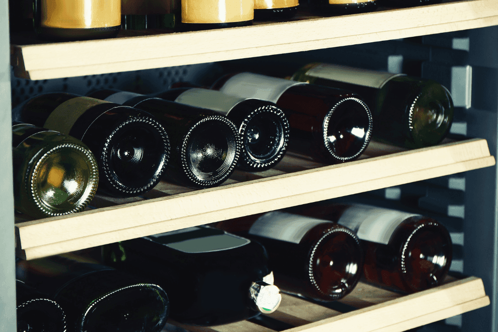 Wine bottles resting on wooden shelves inside a wine cooler